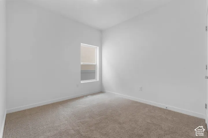 Neutral wall tones, carpet flooring, a single window, and a white door frame