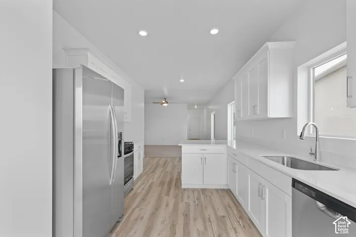 Bright kitchen featuring white cabinetry, light-toned wood-finish flooring, stainless steel appliances, and recessed lighting
