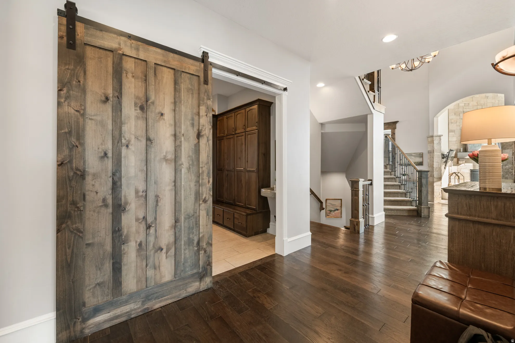 Wide plank wood-finish flooring throughout the entryway, featuring a prominent barn door with black hardware