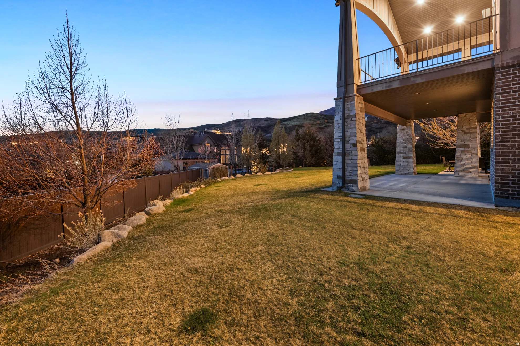 Spacious rear yard with a sloped lawn and mature landscaping