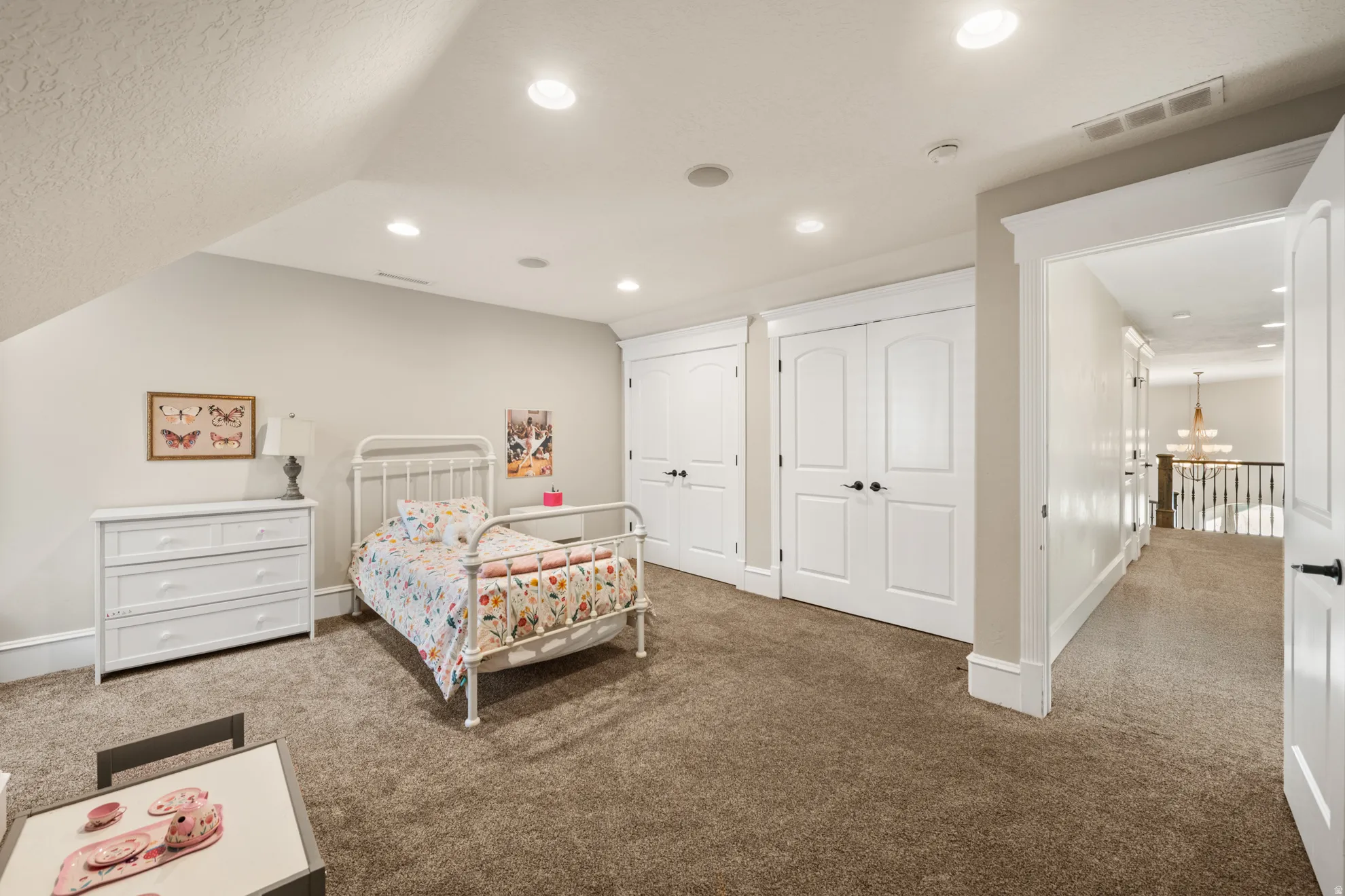 Carpeted room featuring an angled ceiling with recessed lighting, two double-door closets with dark hardware, and a hallway entry
