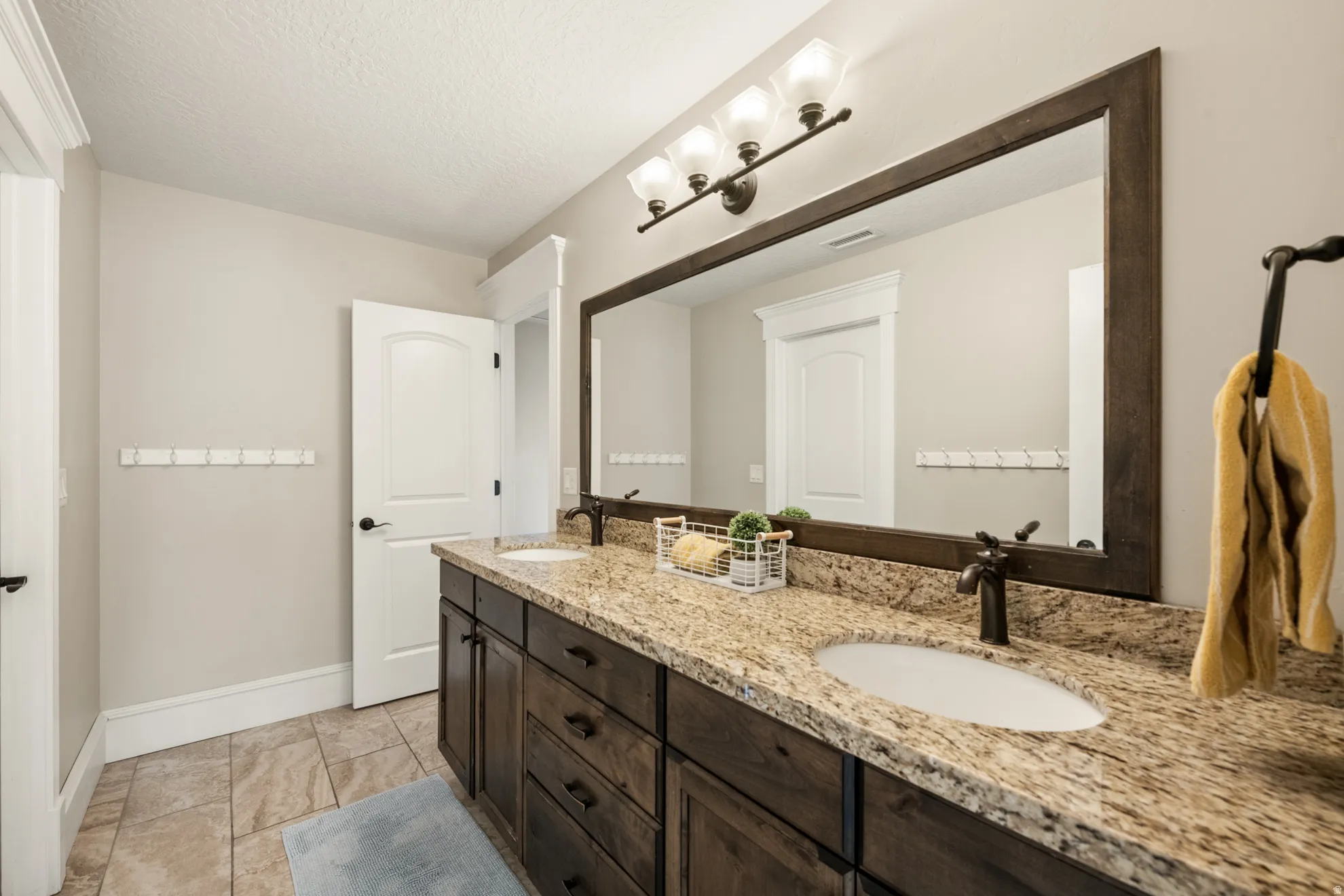 Double vanity featuring a granite countertop, dual undermount sinks, and dark wood cabinetry