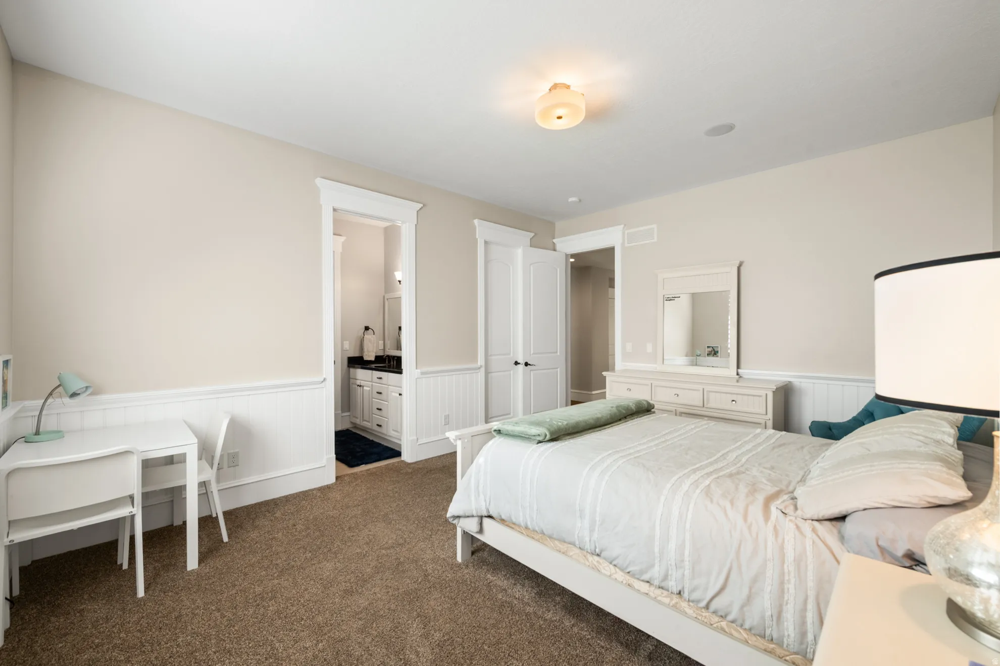 Carpeted room featuring wainscoting, crown molding, and a recessed ceiling speaker