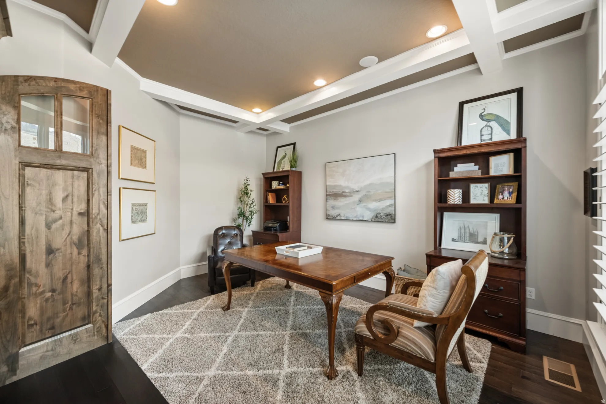 Custom wood door with glass inserts, dark wood-finish flooring, coffered ceiling, recessed lighting, and built-in shelving units