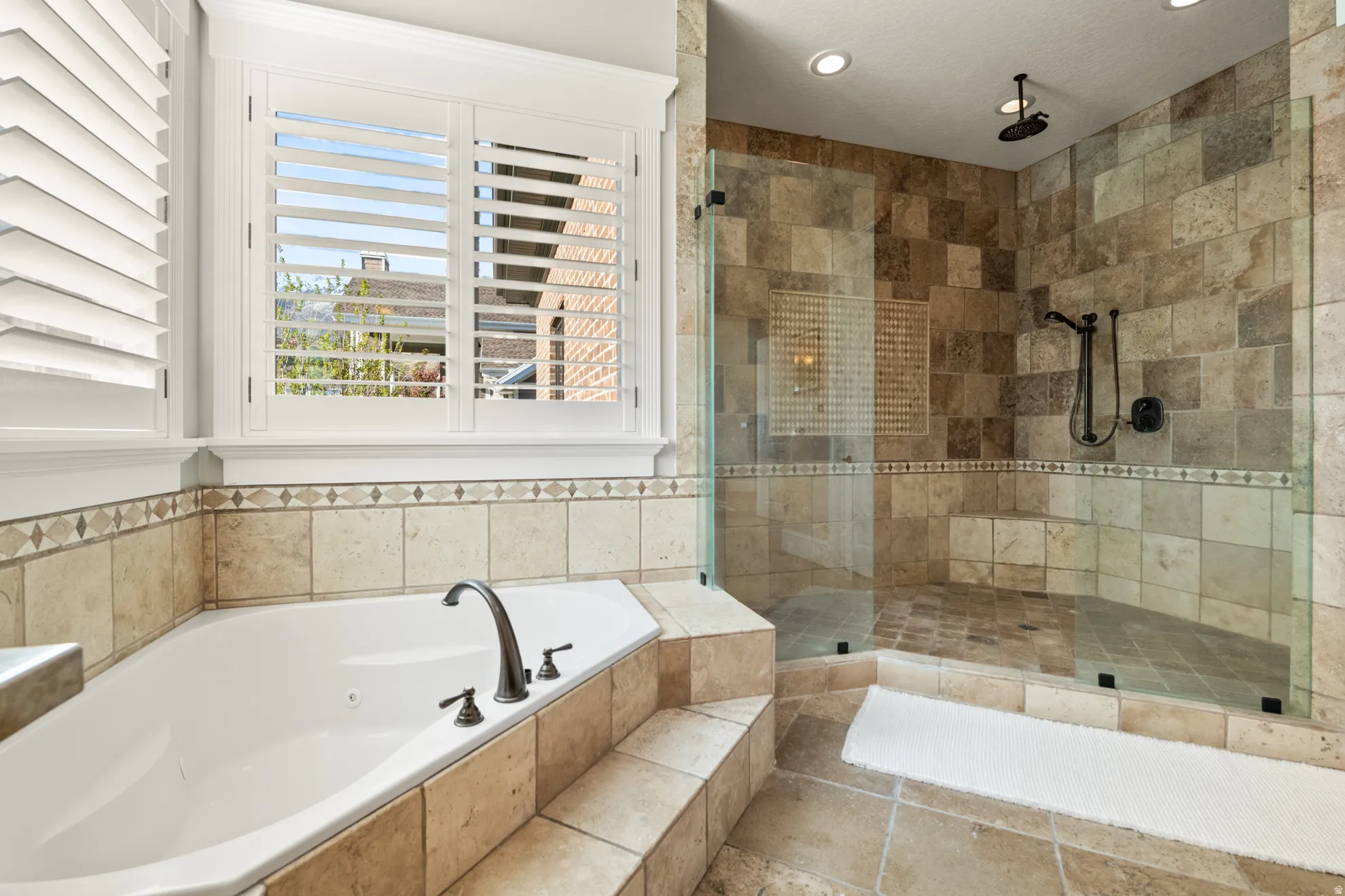 Bathroom featuring a built-in corner soaking tub with deck-mounted bronze faucet and a walk-in shower with glass enclosure