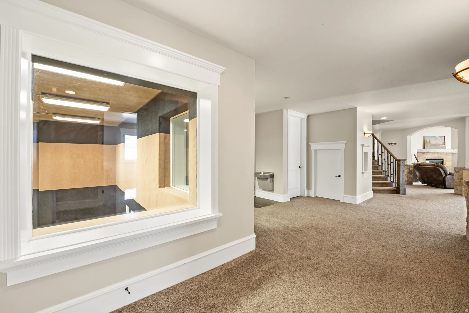 Interior window featuring a soundproof room, broad white trim, and light wood-finish wall panels