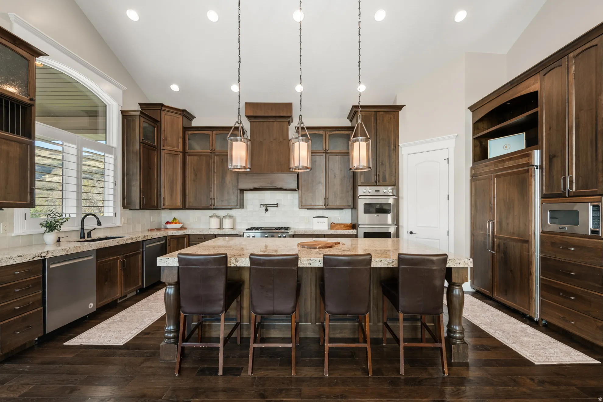 Spacious kitchen featuring an expansive center island with seating, a built-in range, stainless steel appliances, and abundant wood cabinetry
