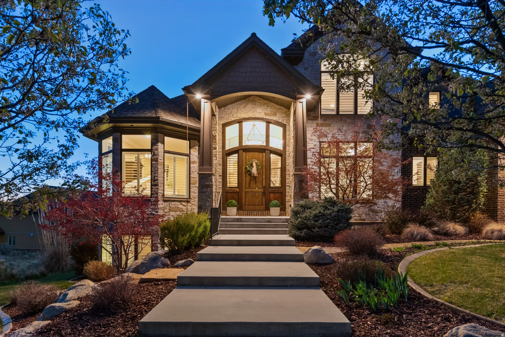 Stone and brick facade featuring a prominent arched entry, a multi-pane front door, and a curved turret with large windows