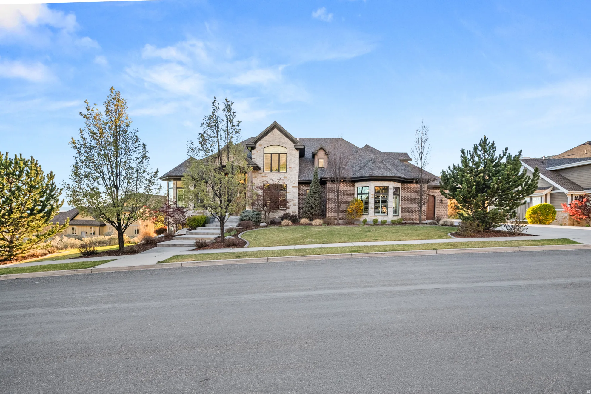 Stone and brick exterior featuring a multi-gabled roofline, a curved bay window, and extensive landscaping