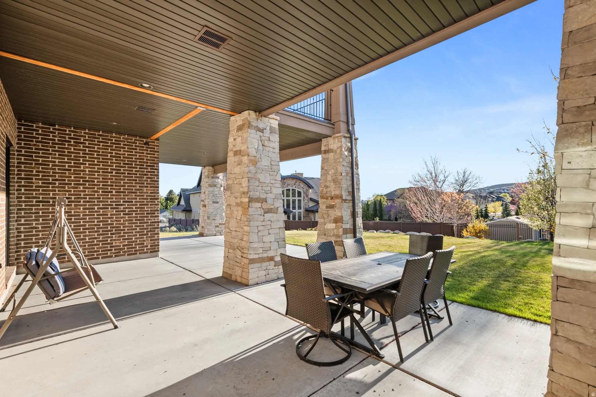 Expansive covered patio with concrete flooring and stone pillars