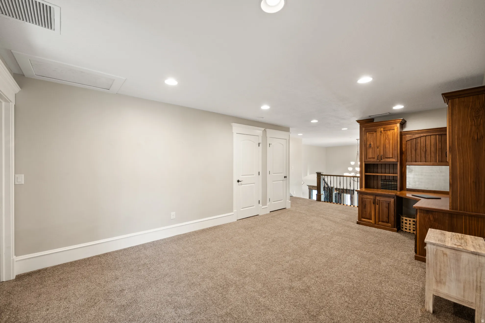 Open loft space featuring built-in wood cabinetry, recessed lighting, and soft carpet flooring