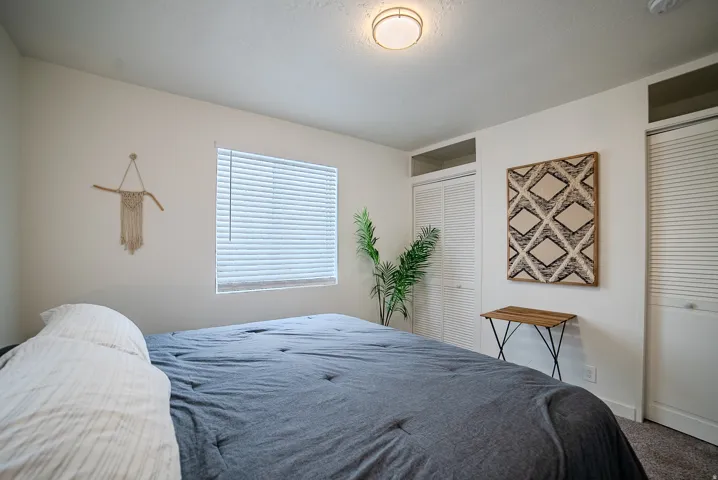Bright room featuring a ceiling-mounted light fixture, a window with horizontal blinds, and carpeted flooring