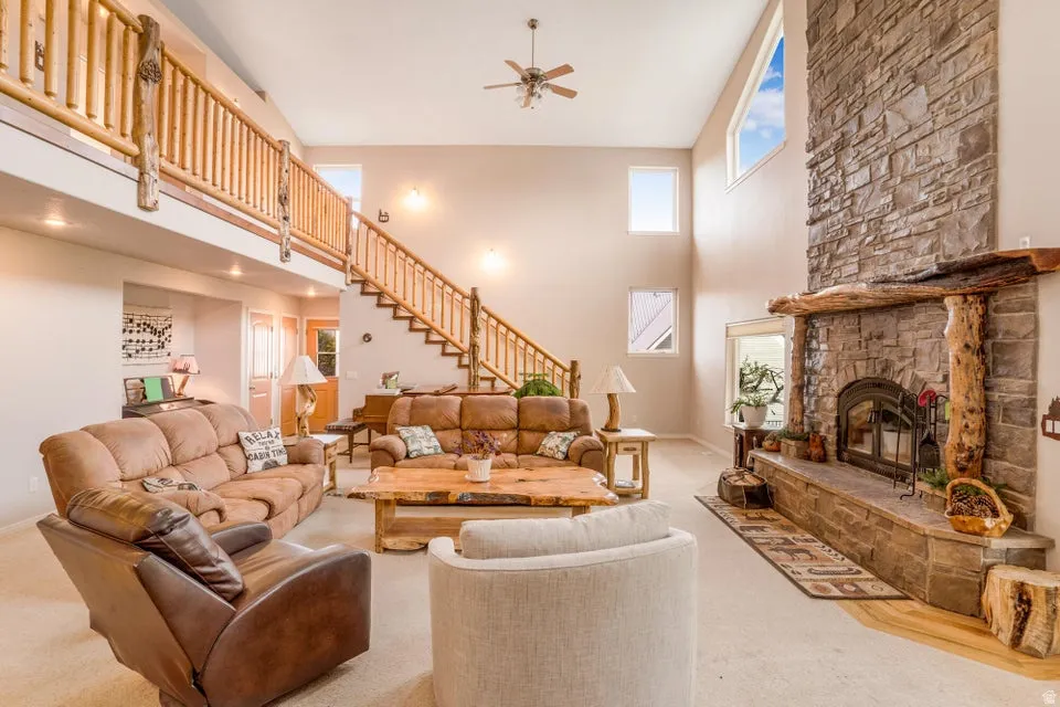 Great room featuring a vaulted ceiling, stone-clad fireplace with wood mantle, lofted walkway, and a rustic wood staircase