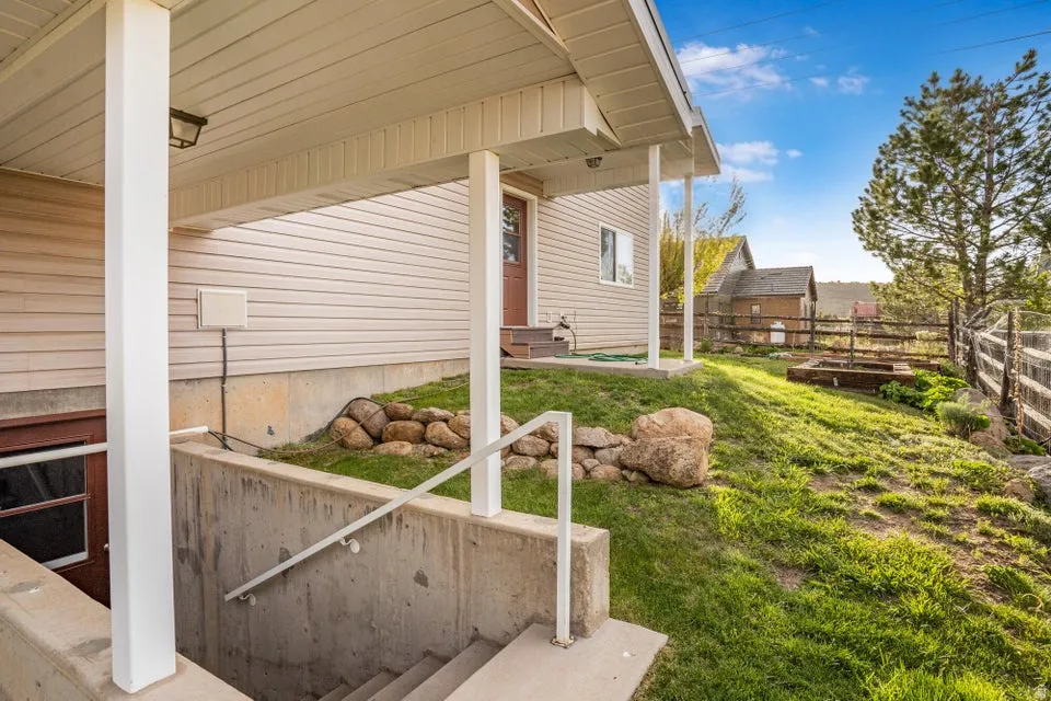 Sloped lawn area with concrete steps descending to a lower level entry