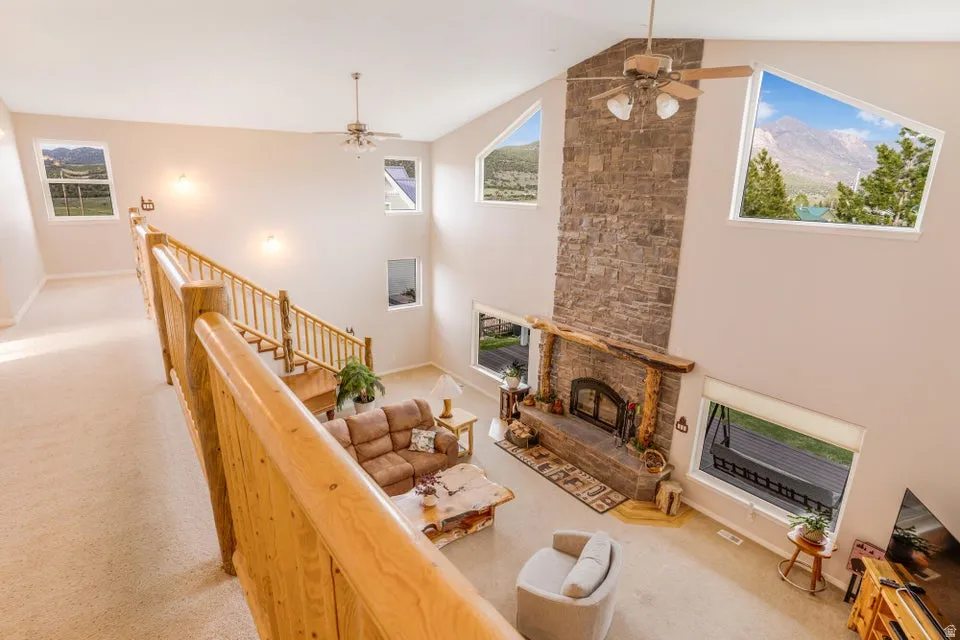 Two-story living area featuring a floor-to-ceiling stone-clad fireplace and a wood mantel