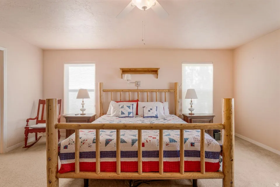 Comfortable interior space featuring two windows with blinds, a ceiling fan, and carpeted flooring
