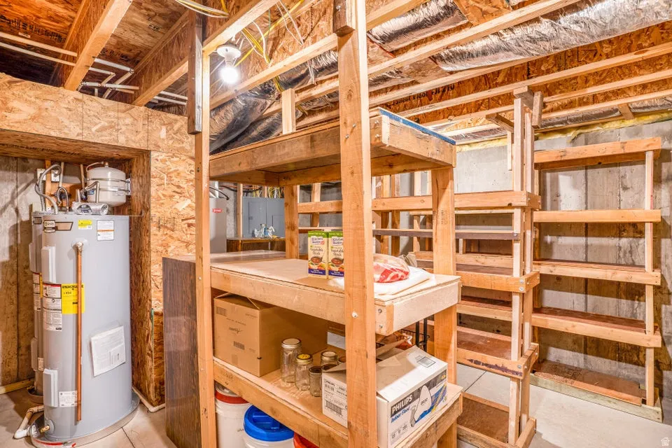 Unfinished basement area featuring exposed wood joists and concrete walls, overhead lighting, and built-in wood shelving units