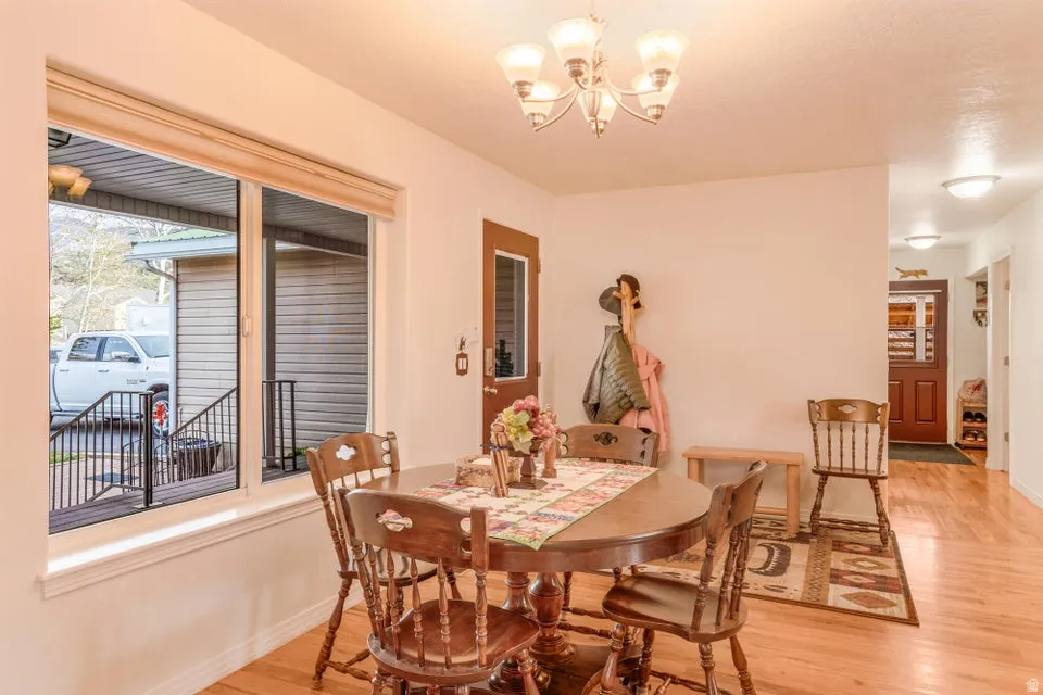 Dining area featuring wood-finish flooring, a multi-pane window with a roller blind, and a five-light chandelier