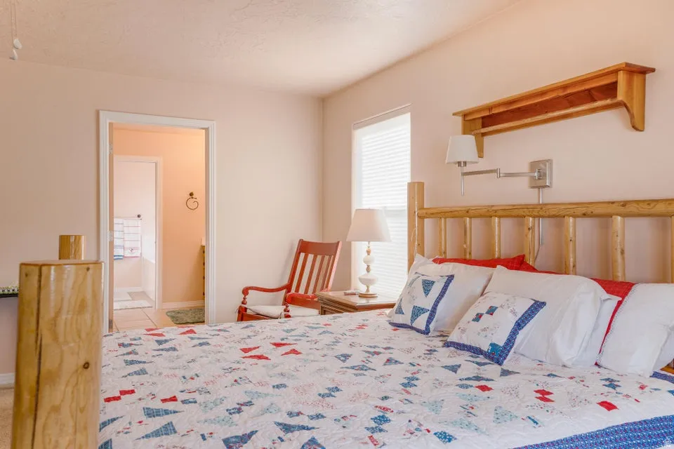Bedroom featuring a log-style bed frame, an integrated wall-mounted swing arm lamp, and a window with blinds