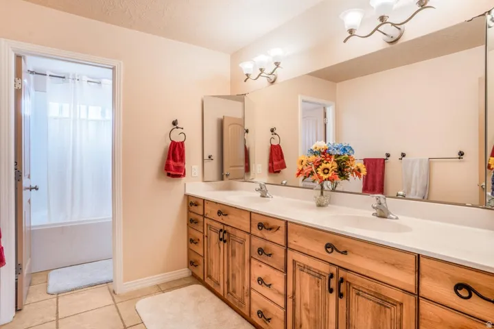 Dual vanity featuring wood cabinetry with decorative hardware, white countertops, and integrated sinks