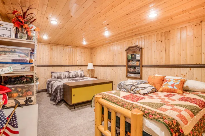 Wood-paneled walls and ceiling creating a rustic ambiance, complemented by recessed lighting and a carpeted floor