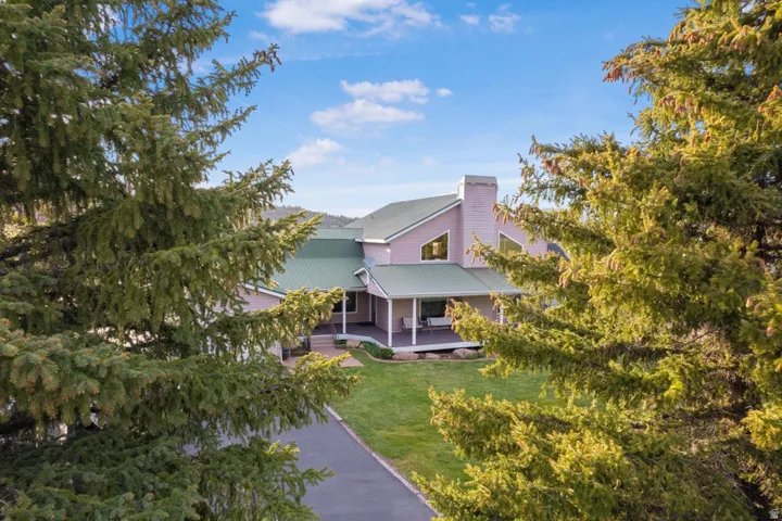 Spacious property featuring a large home with a green metal roof, multiple gables, and a prominent chimney