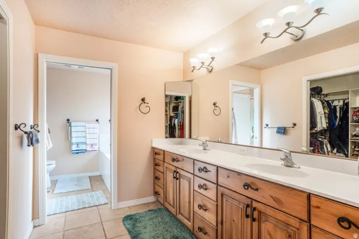 Double vanity featuring wood cabinetry with decorative hardware, white countertops, and dual integrated sinks