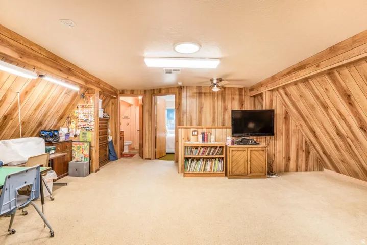 Expansive room featuring wood-paneled walls and ceiling, wall-to-wall carpeting, and multiple doorways