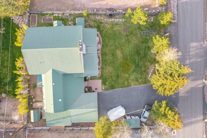 Property featuring a green metal roof, a paved driveway, and a manicured lawn