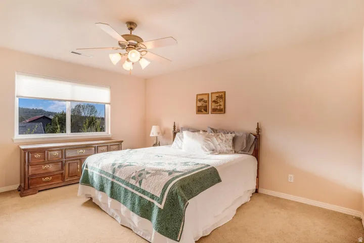 Bedroom featuring a ceiling fan with integrated lighting, a large window, and carpet flooring