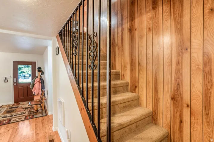 Carpeted staircase with wrought iron balusters and a wood handrail