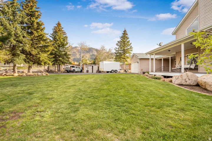 Expansive green lawn with mature evergreen trees and a decorative rock border