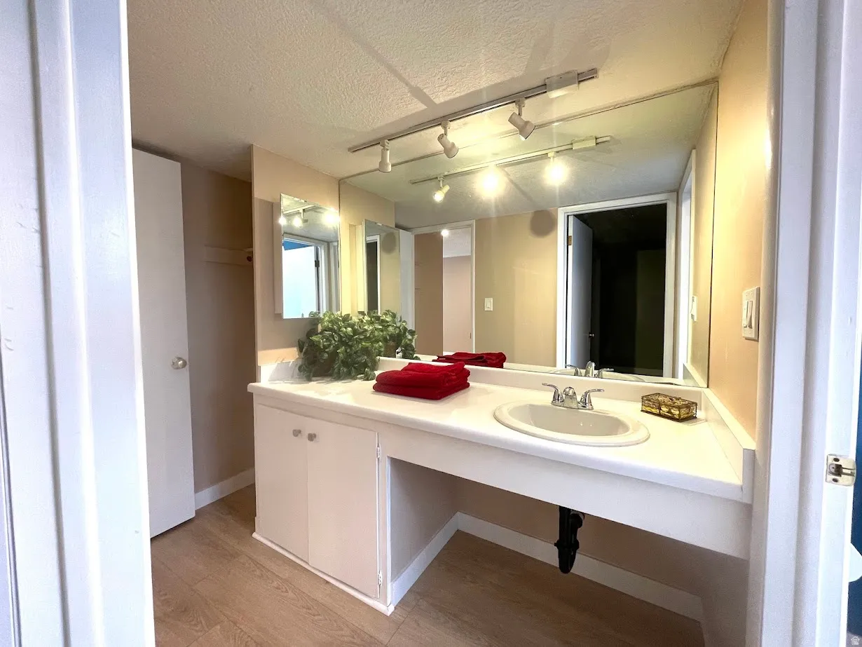 Vanity area featuring a large wall-mounted mirror, track lighting, and a white countertop with an integrated sink