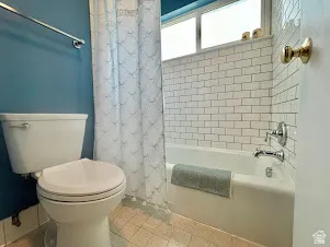 Bathroom with white subway tile shower surround, chrome fixtures, and a dual-pane window above the tub