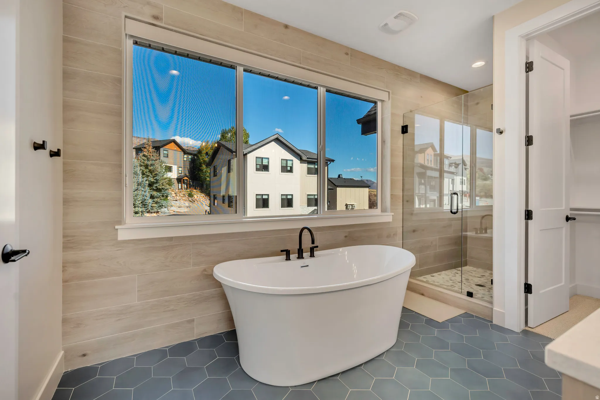 Full bathroom with a freestanding bath, tile patterned flooring, a stall shower, and tile walls