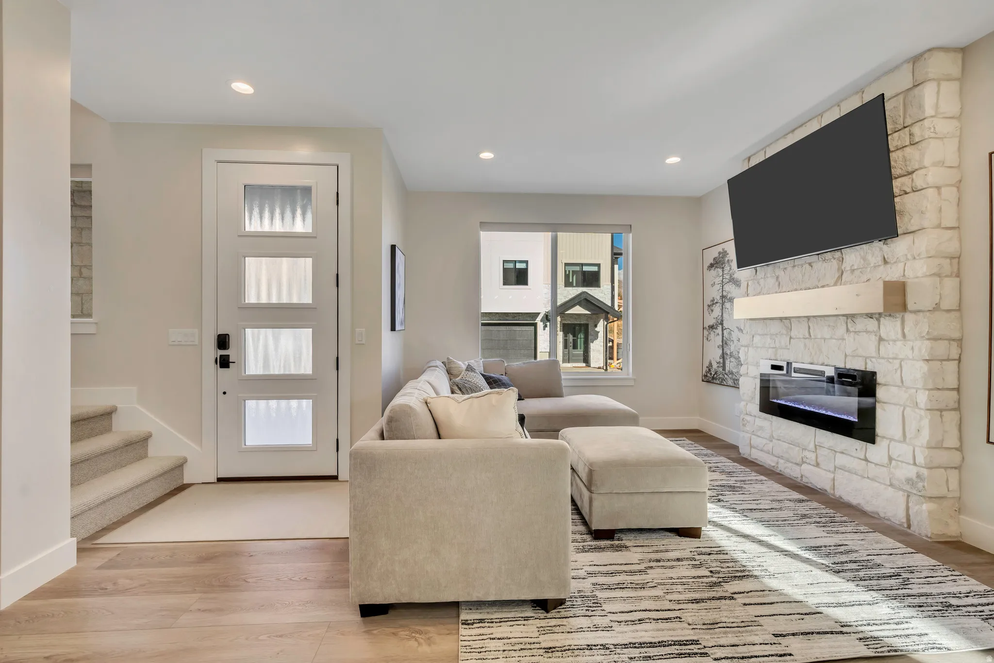 Living area featuring light wood-style flooring, a stone fireplace, and recessed lighting