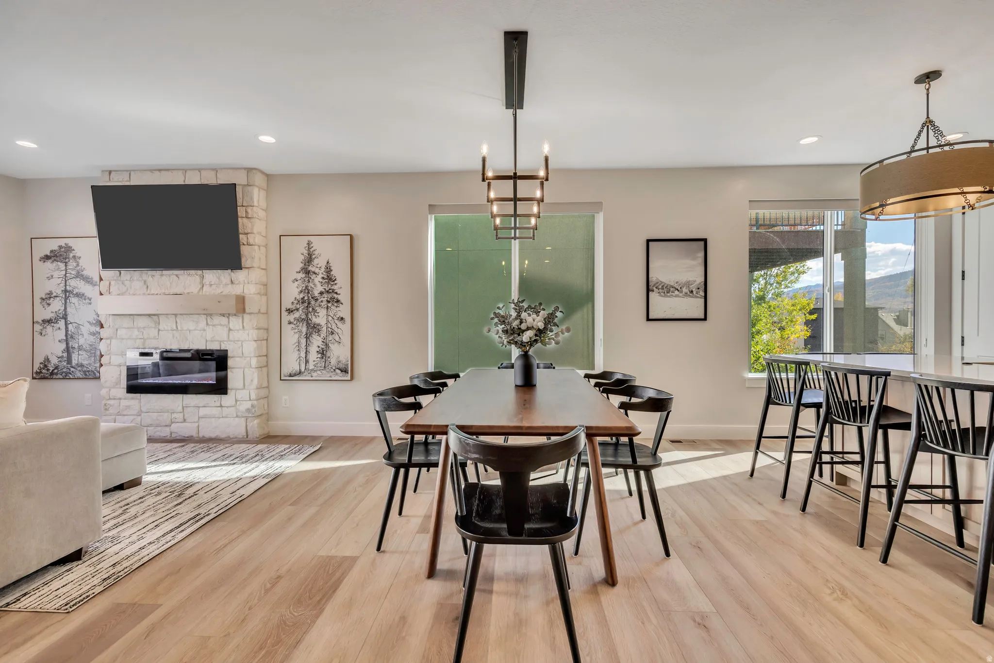 Dining room with a fireplace, light wood-style flooring, and hanging lights