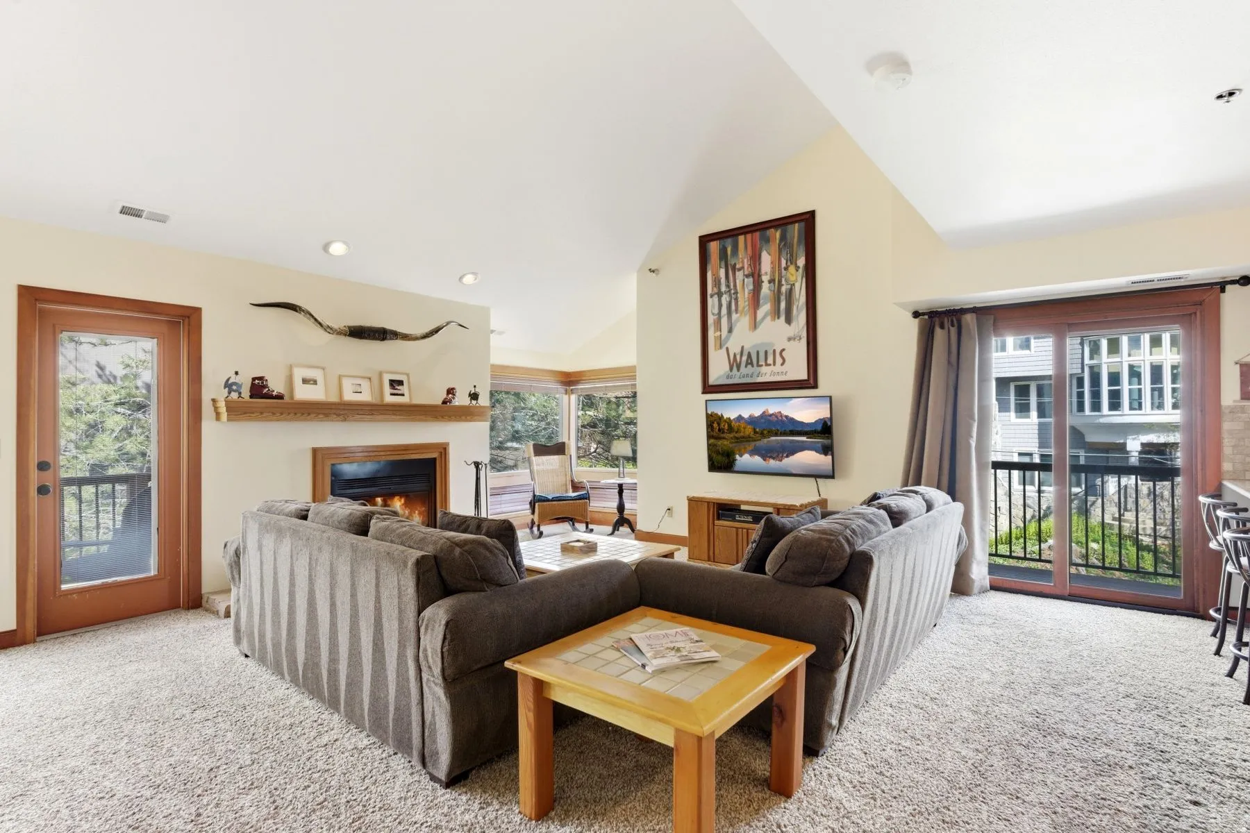 Living area featuring vaulted ceilings, a built-in fireplace with wood mantel, and plush carpeting