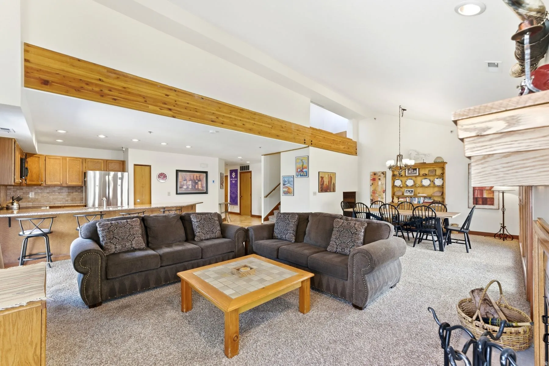 Open-concept living area featuring high vaulted ceilings with exposed wood beams