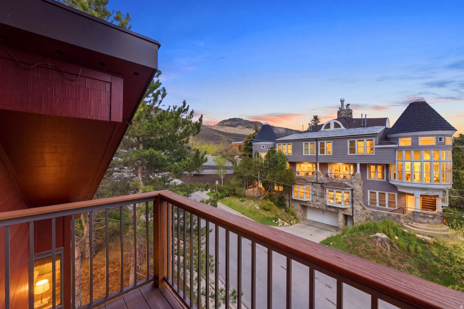 Balcony with wood-finish railing and metal spindles overlooking a multi-level residence