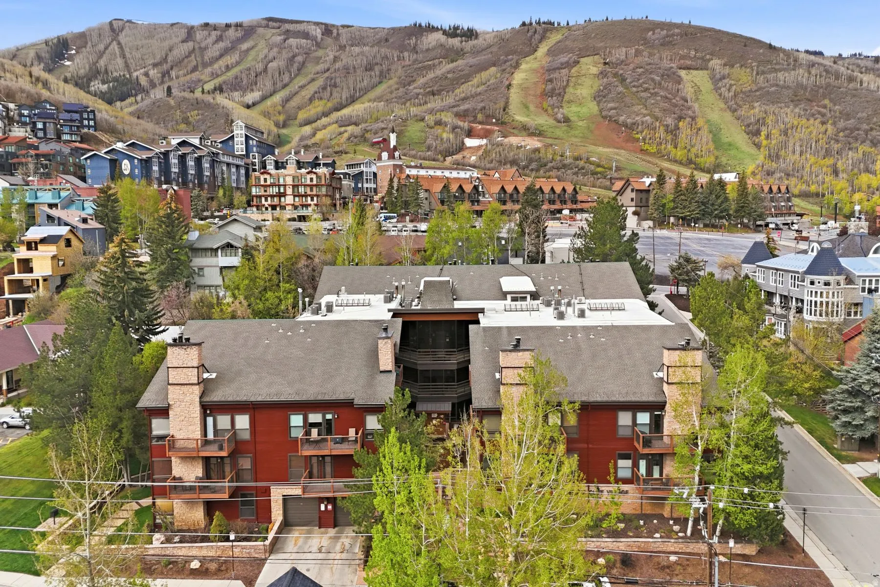 Contemporary multi-level building featuring a red facade, multiple private balconies with metal railings, and stone chimney accents