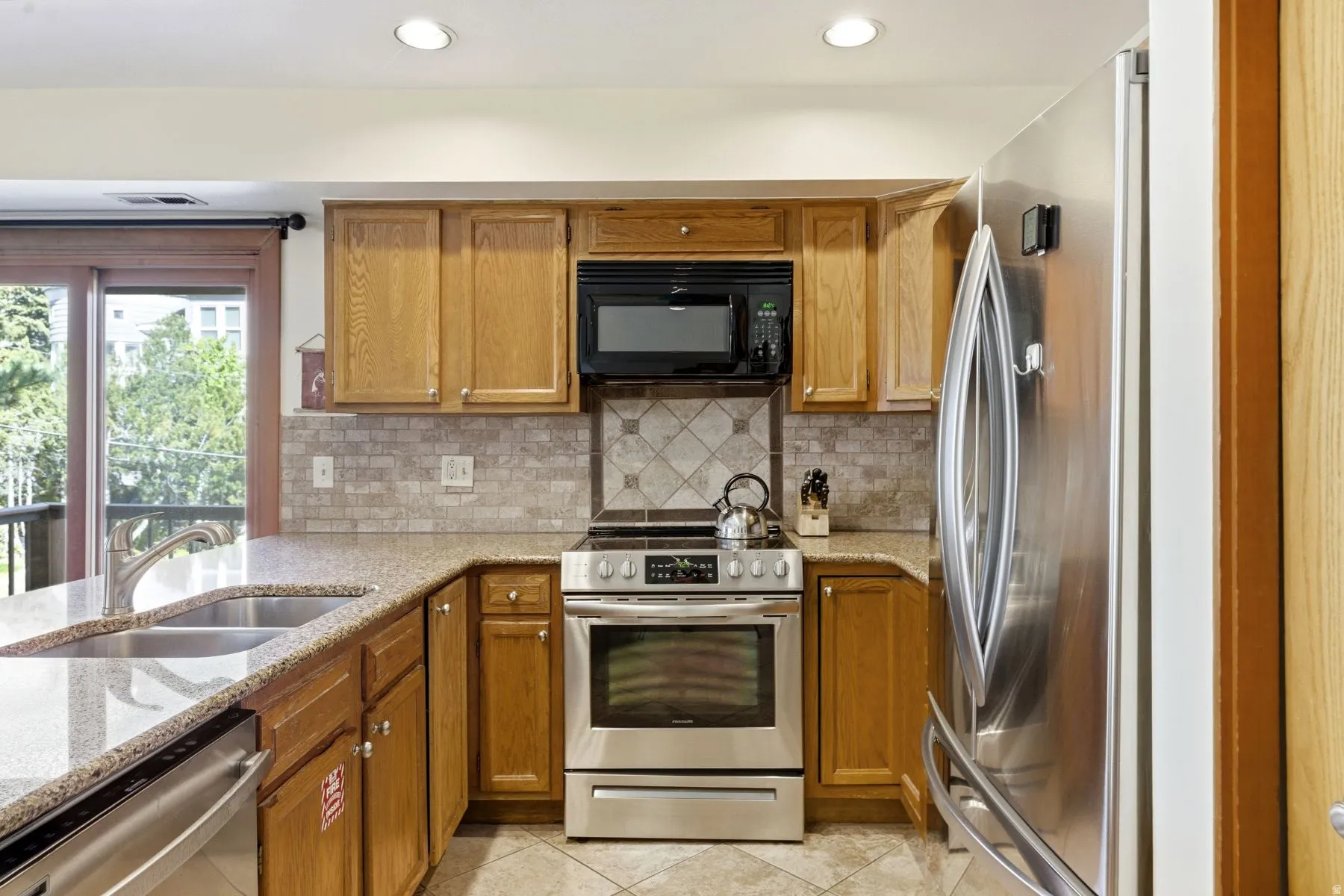 Kitchen featuring wood cabinetry, stainless steel appliances, speckled countertops, and a tiled backsplash