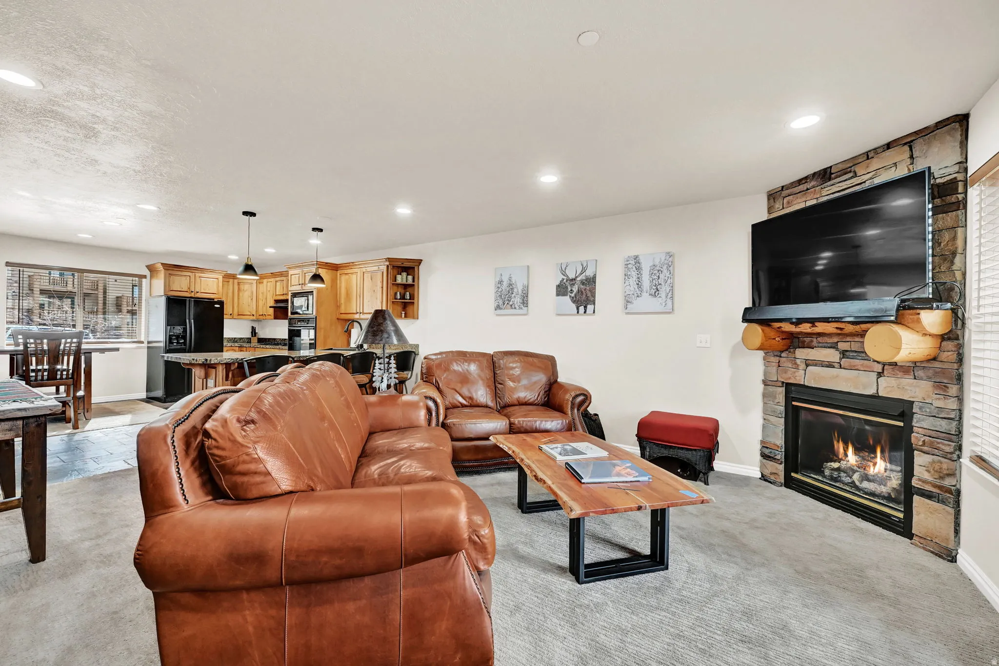 Living area featuring a stone-clad fireplace with a log mantel, recessed lighting, and light-toned wall finishes