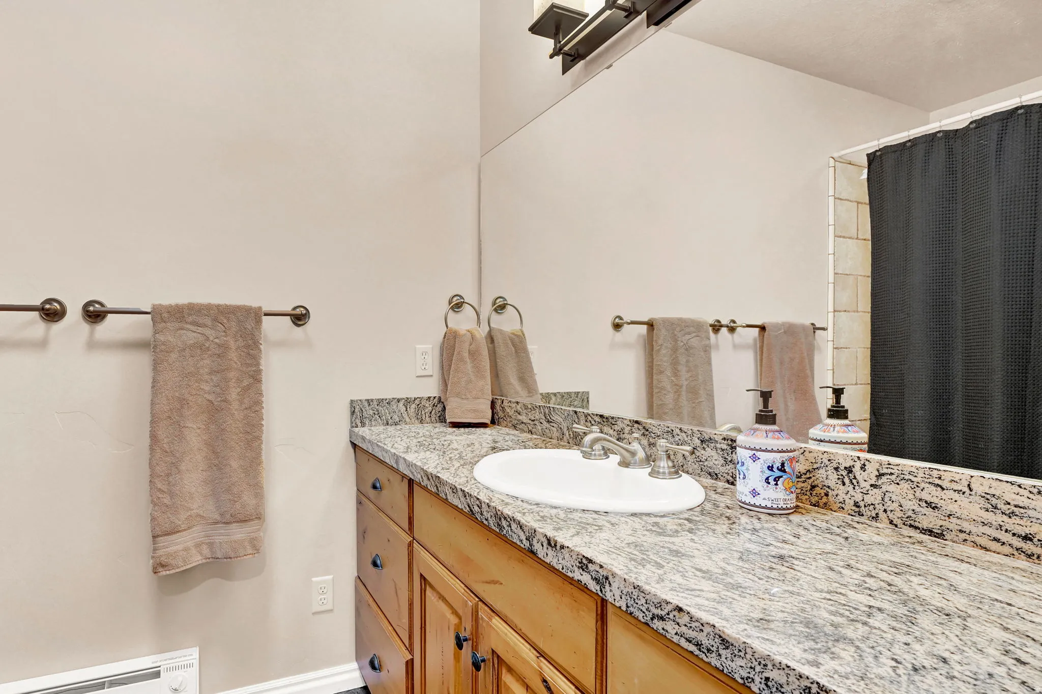 Bathroom vanity featuring a light-toned granite countertop with an undermount sink and brushed nickel faucet