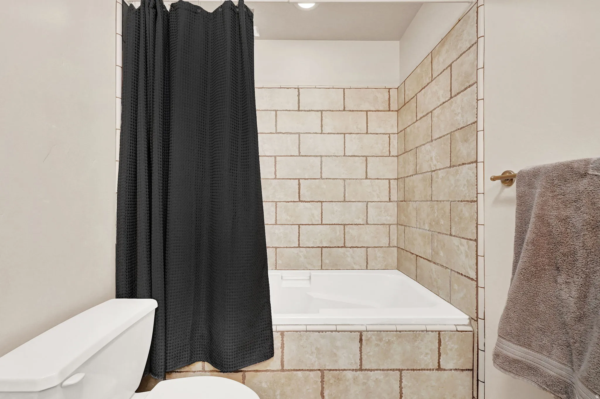 Tub and shower combination featuring beige subway tile surround