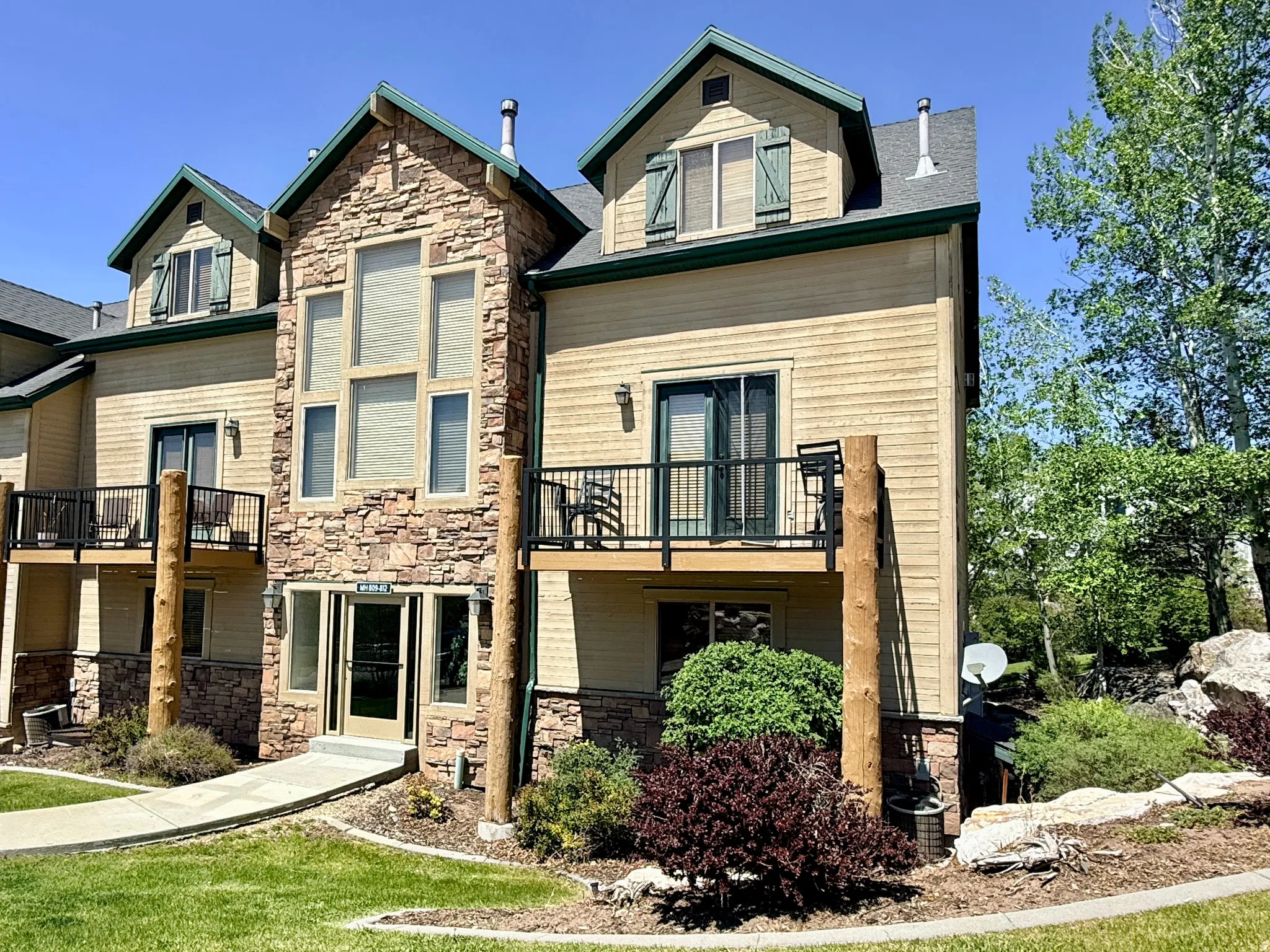 Multi-level condominium building featuring stone accents and light-colored siding