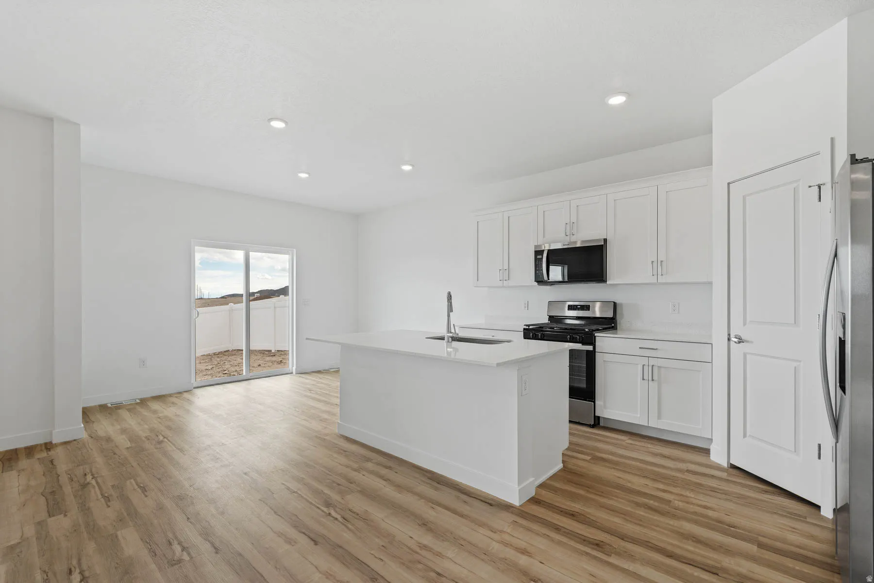 Modern kitchen and dining area featuring wood-finish flooring, recessed lighting, and white walls