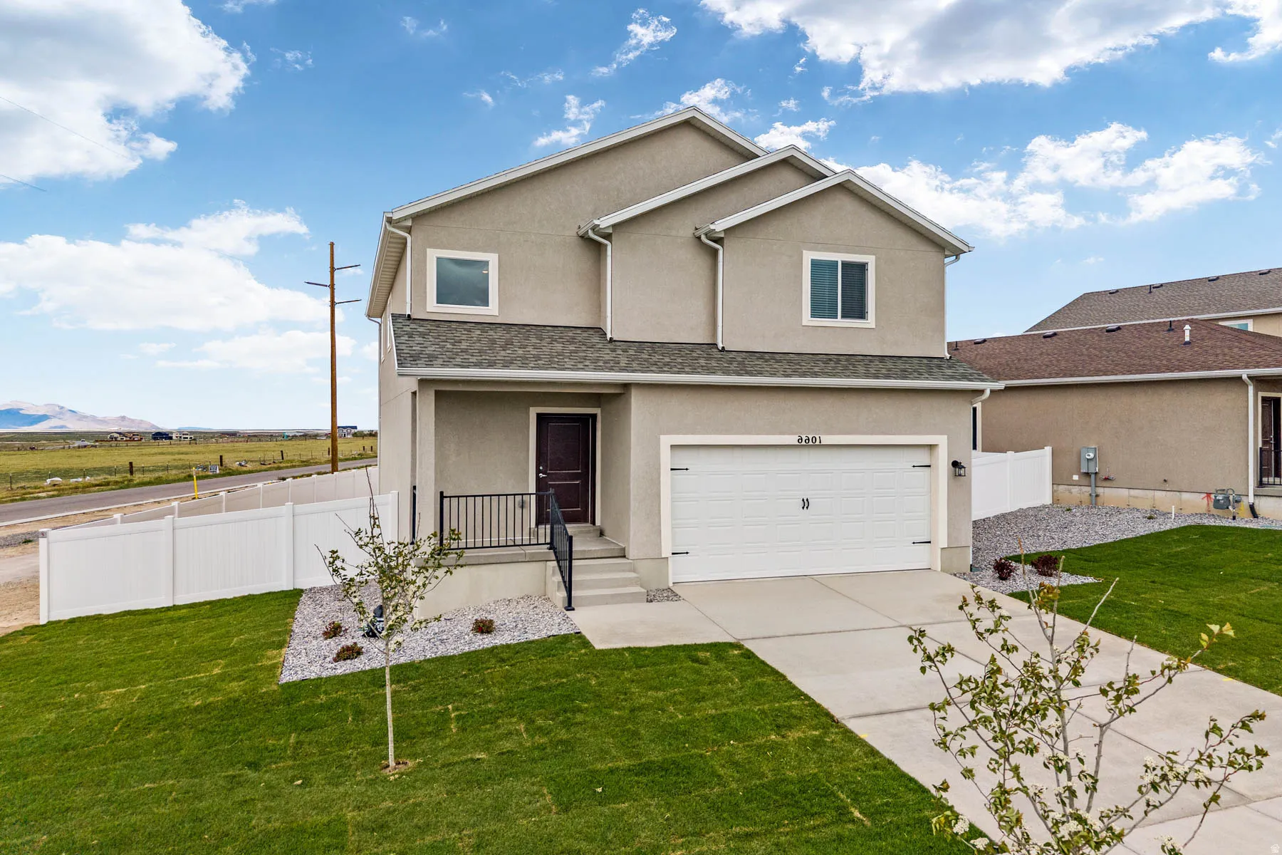 Two-story stucco residence featuring a two-car garage, concrete driveway, and a welcoming covered porch