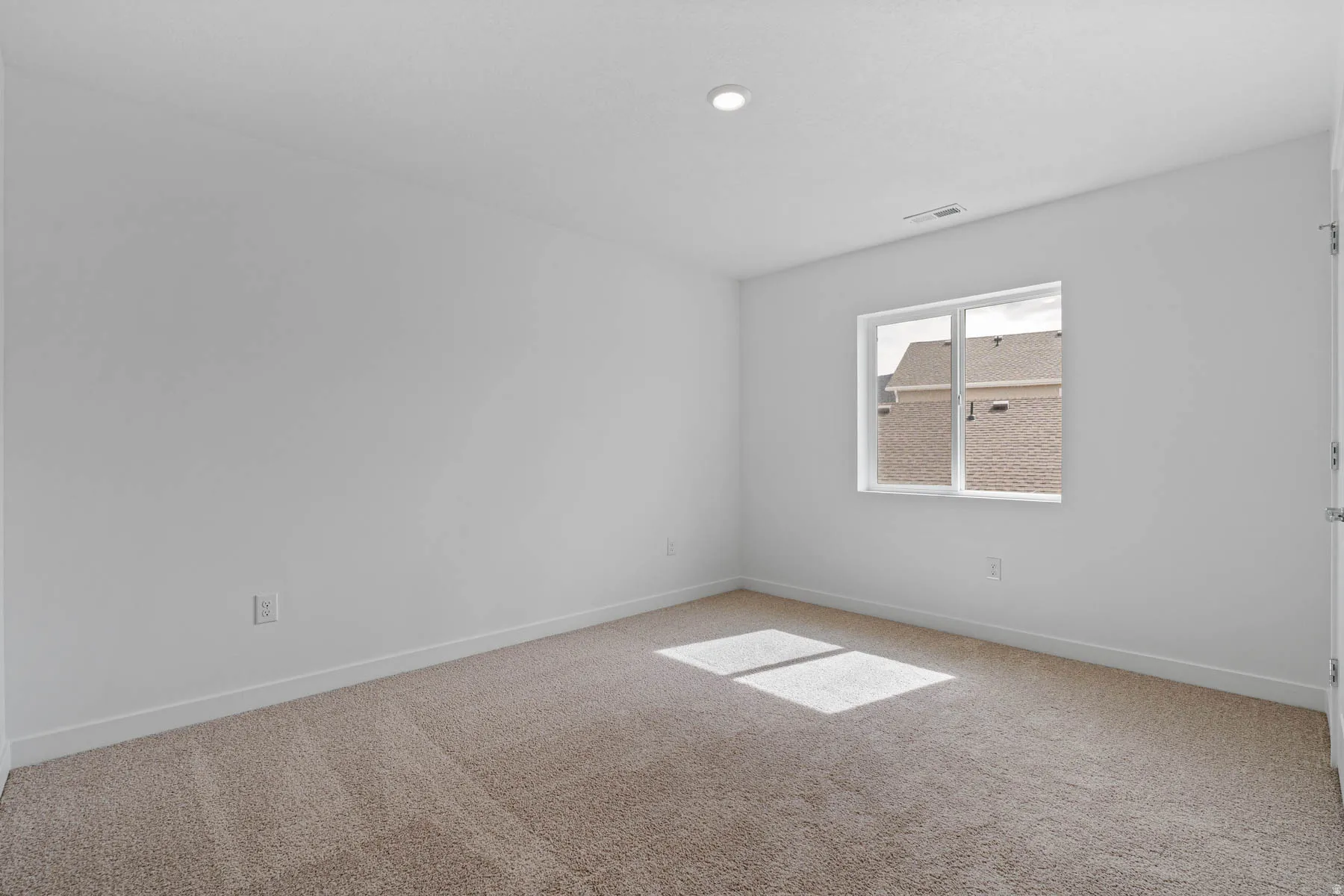 Bright interior space featuring a window, recessed lighting, and neutral-toned carpeting