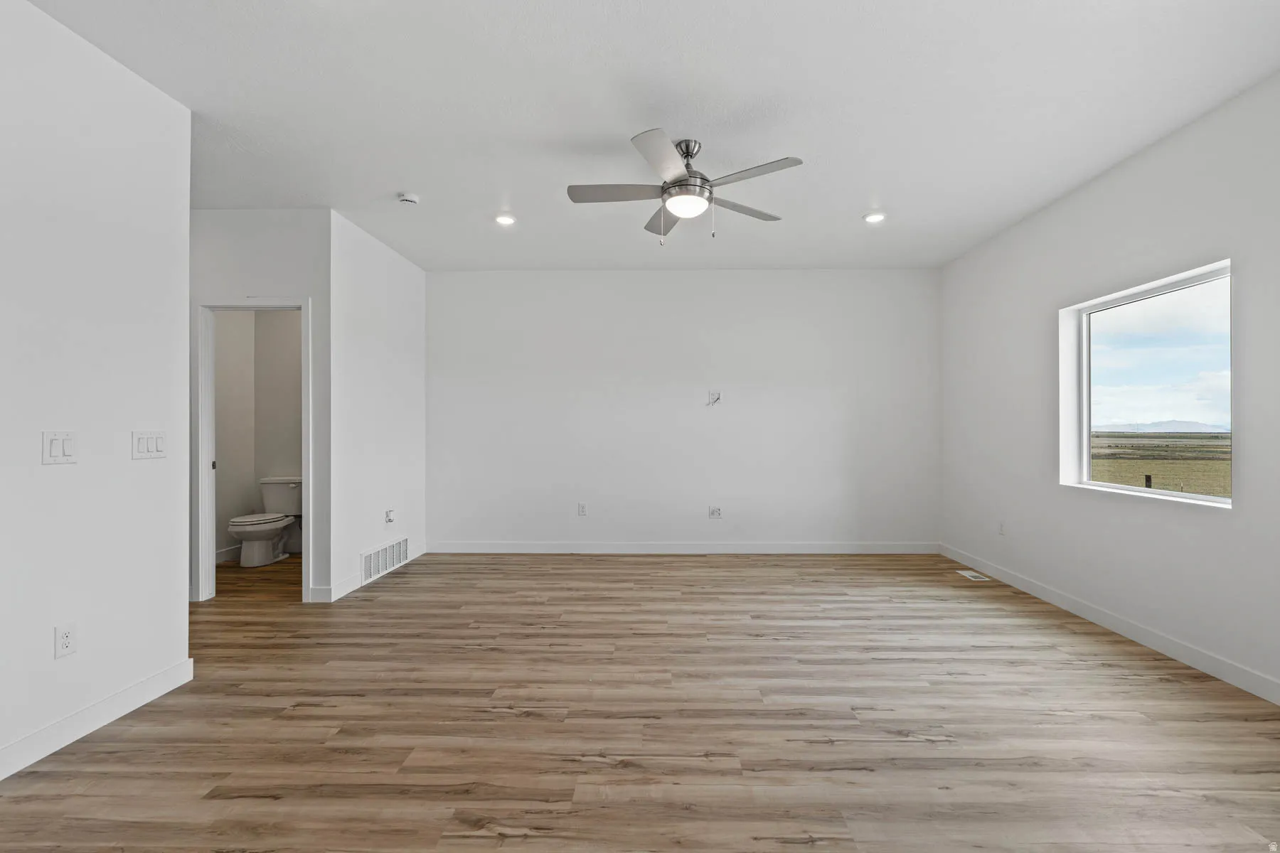 Spacious interior room featuring wood-finish flooring, recessed lighting, and a ceiling fan with integrated light fixture